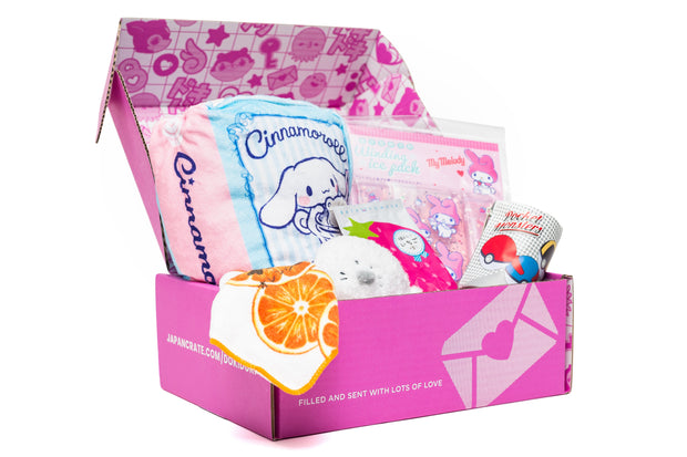 The Doki Doki Kawaii Crate by Japan Crate is a pink subscription box filled with kawaii Cinnamoroll-themed items, Japanese plushies, snacks, and toys, all showcased on a white background.